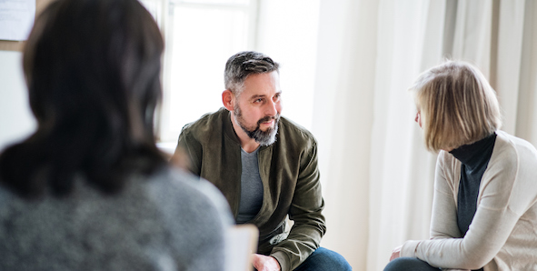 Mature man and senior women sitting in a circle during group therapy, talking.